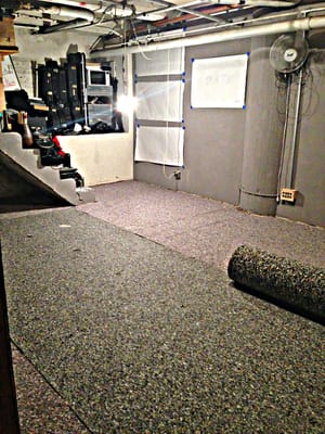 Photo of a basement with musical instruments lifted up off the floor, and carpeting halfway installed